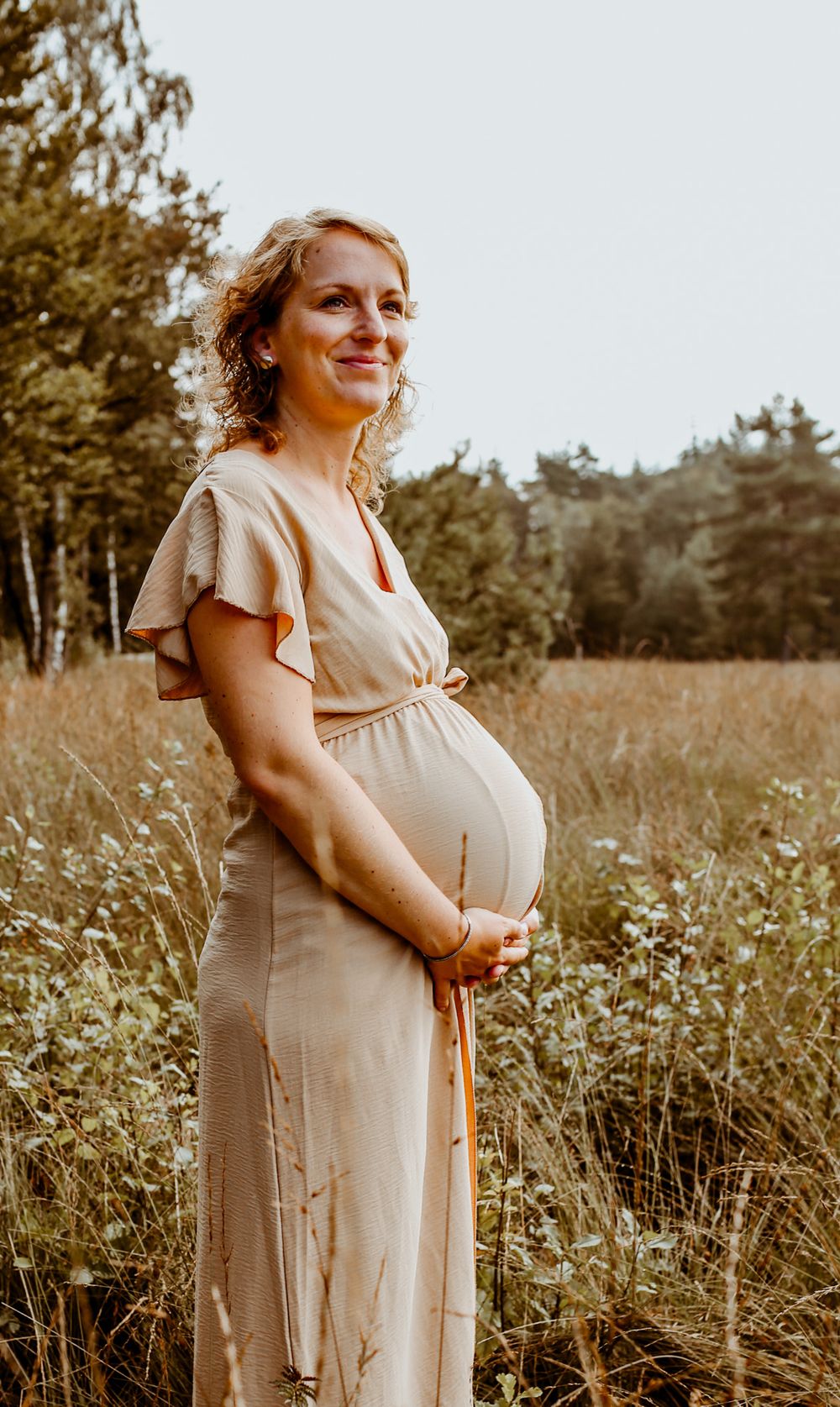 Maternity photo shoot in a wildflower meadow during golden hour.