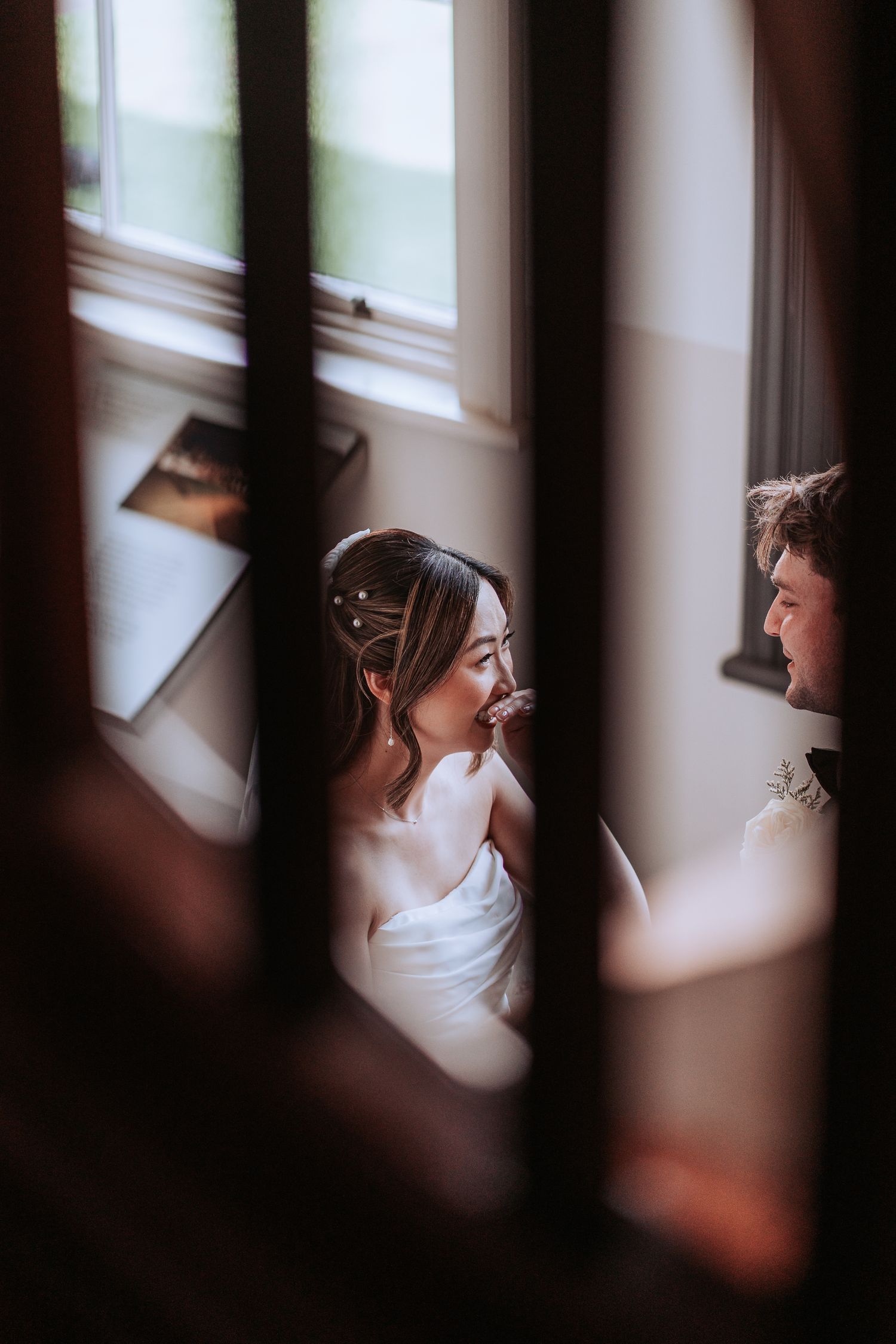 A candid wedding moment framed through architectural elements with soft lighting.