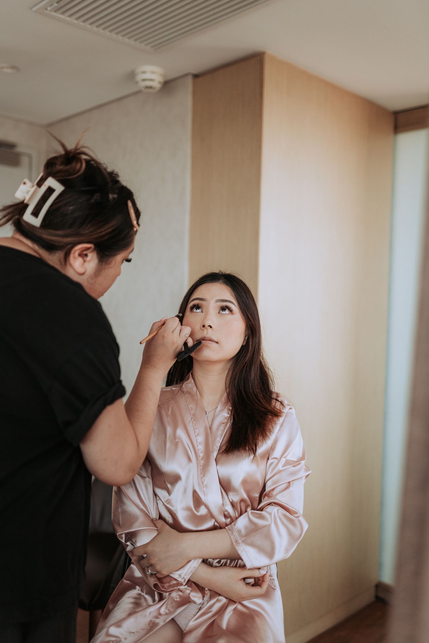 Professional makeup artist applying cosmetics in a well-lit room.