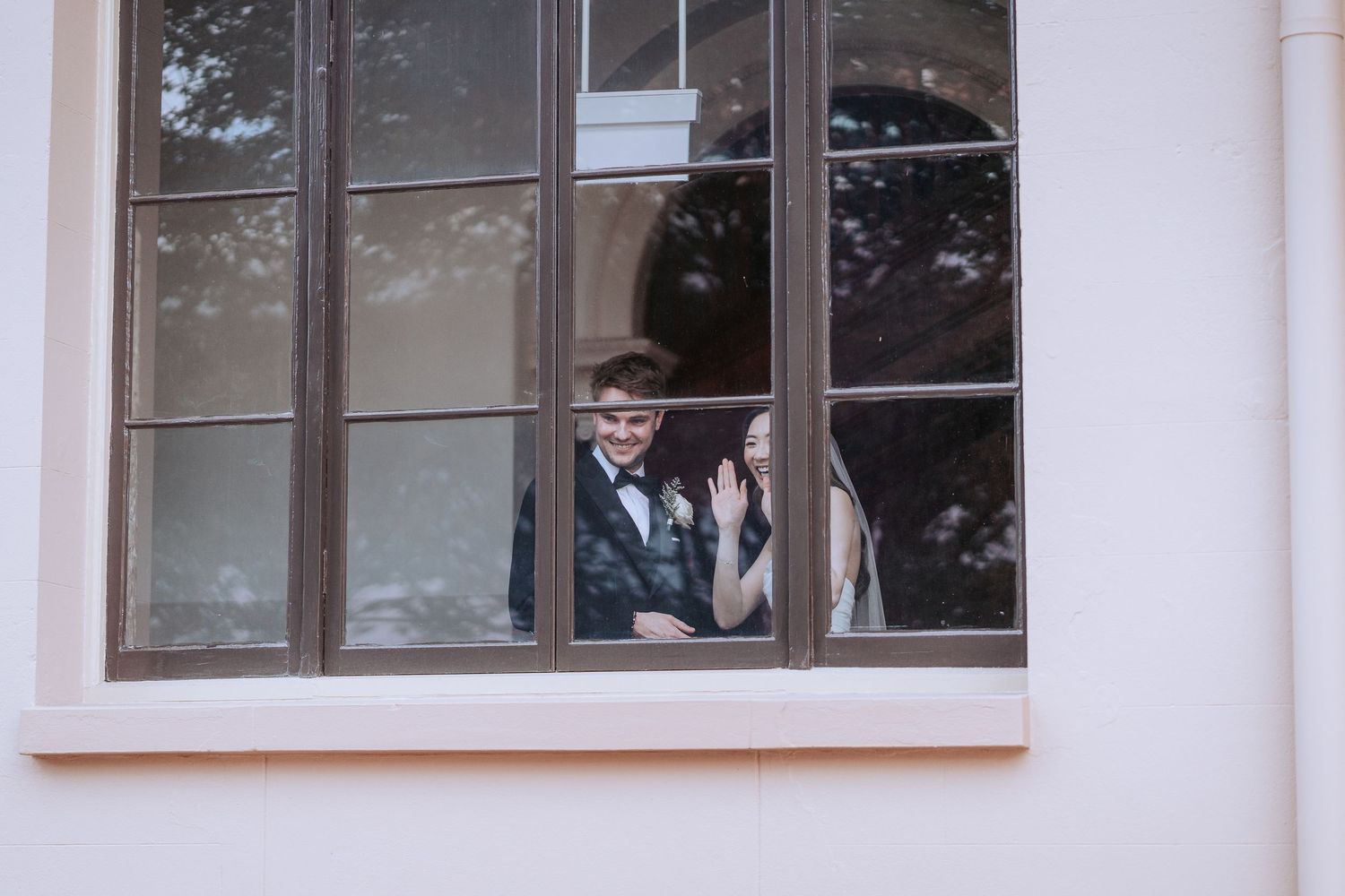 Wedding couple shares an intimate moment through a window frame.