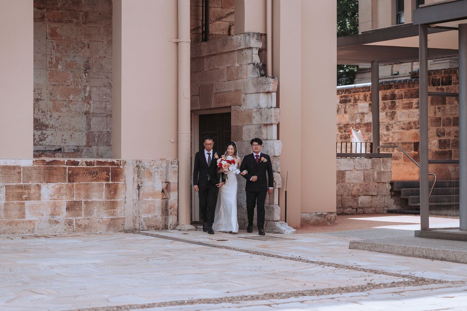 Wedding couple walks through stone archway during ceremony.