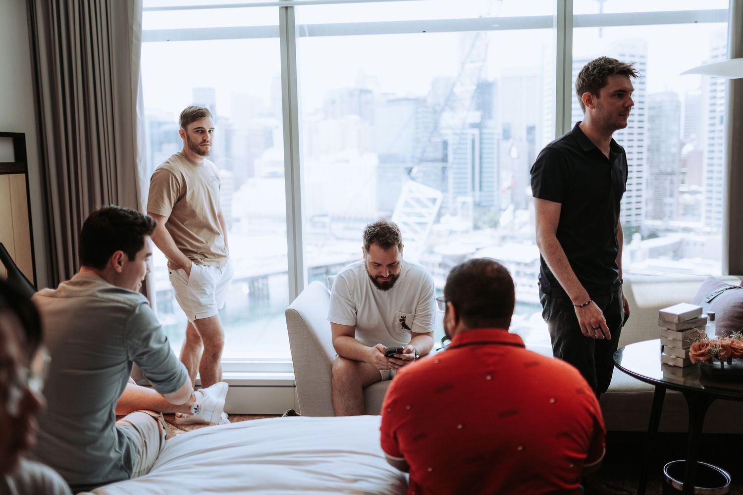 Group of men gathered in a modern high-rise room with city views.