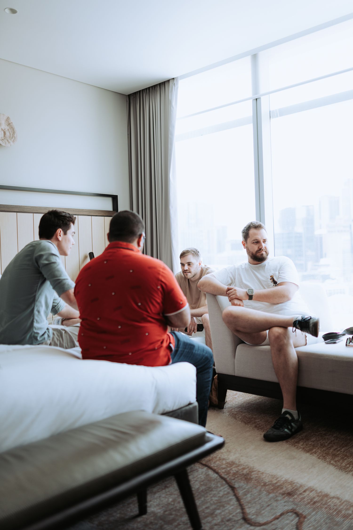 Group of friends relaxing and socializing in a modern hotel room with city views.