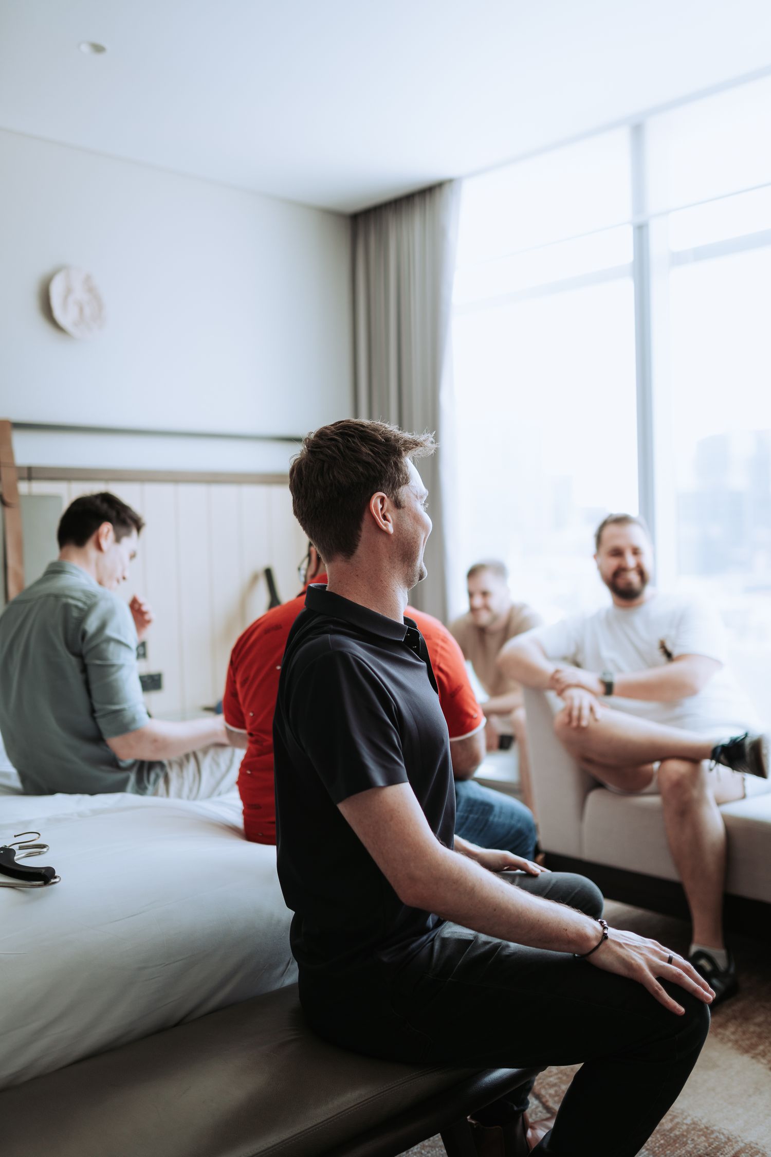 Friends gathered in a hotel room having casual conversation by the window.