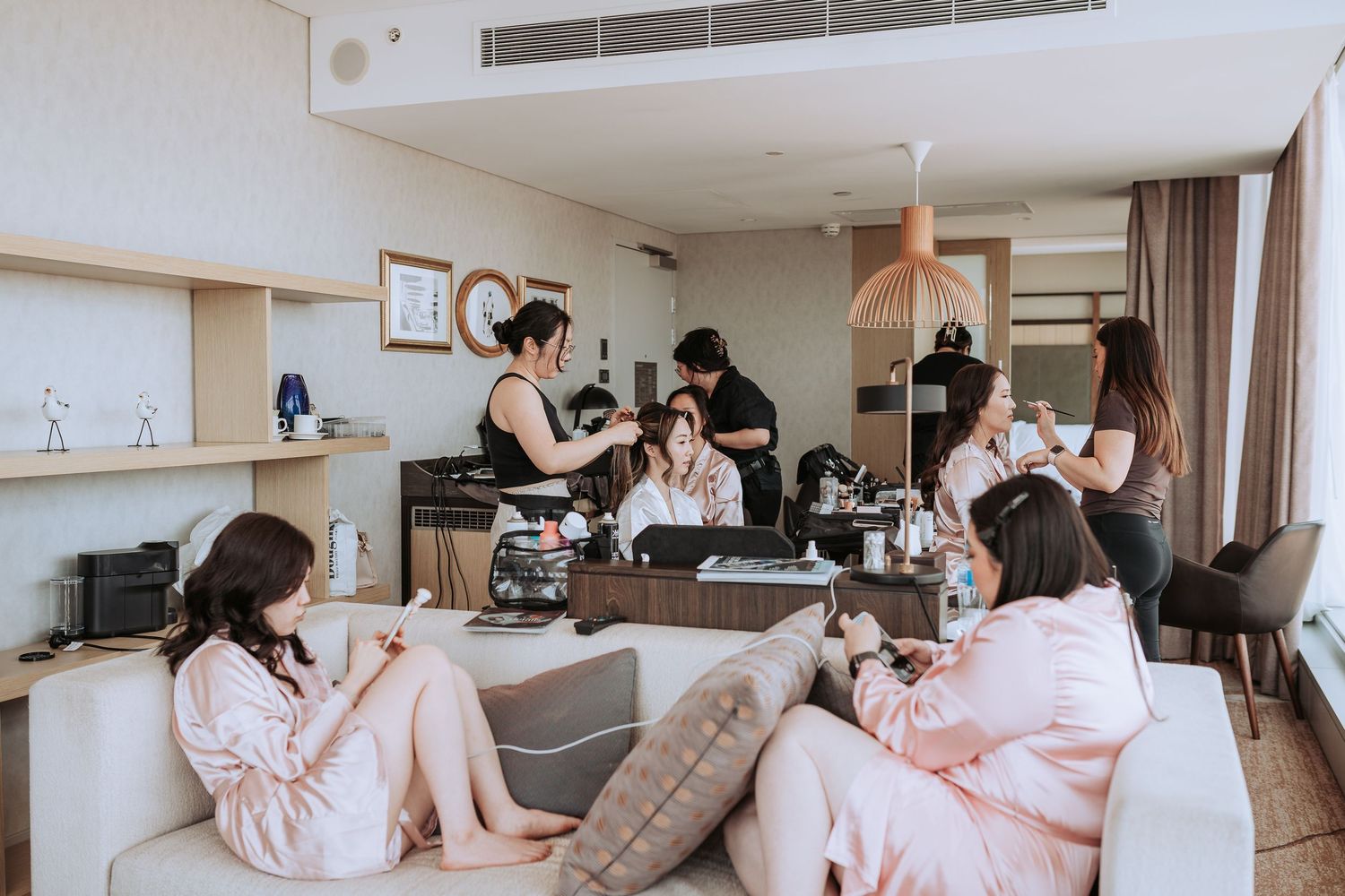 Bridal party relaxes in pink robes during wedding morning preparations.
