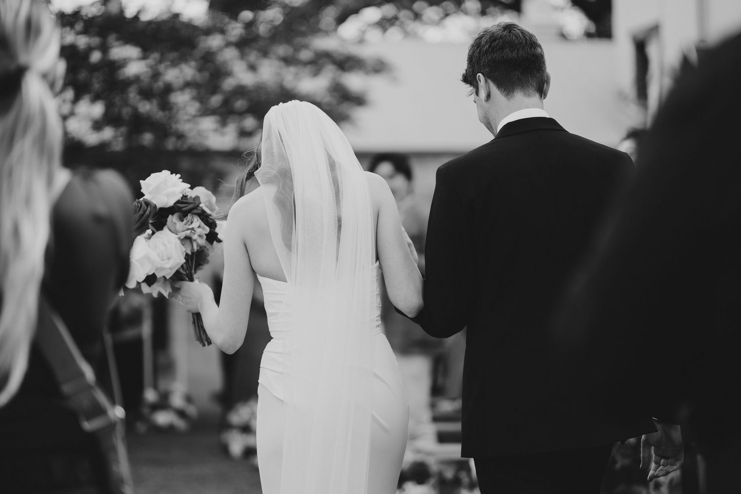 Black and white photo of newlyweds walking together during their wedding ceremony.