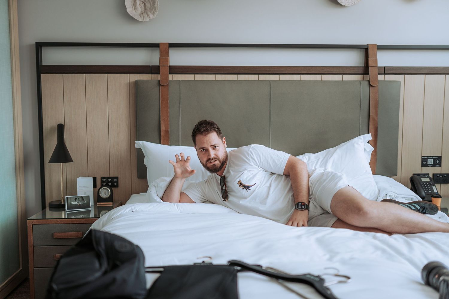 Person lounging on a modern hotel bed with wooden headboard.