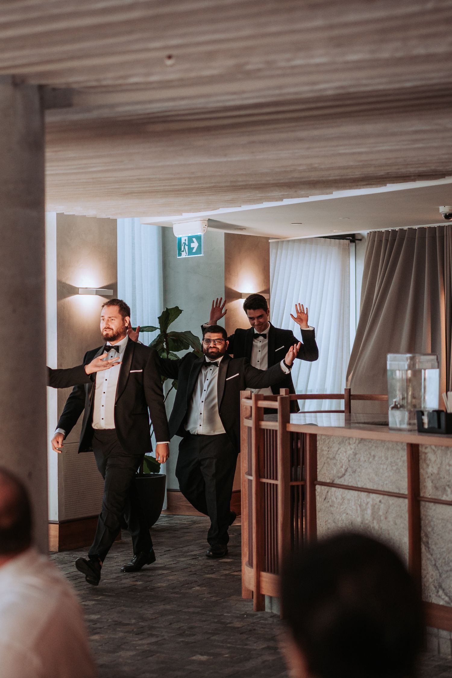 Wedding party members dance and celebrate during reception entrance in formal attire.