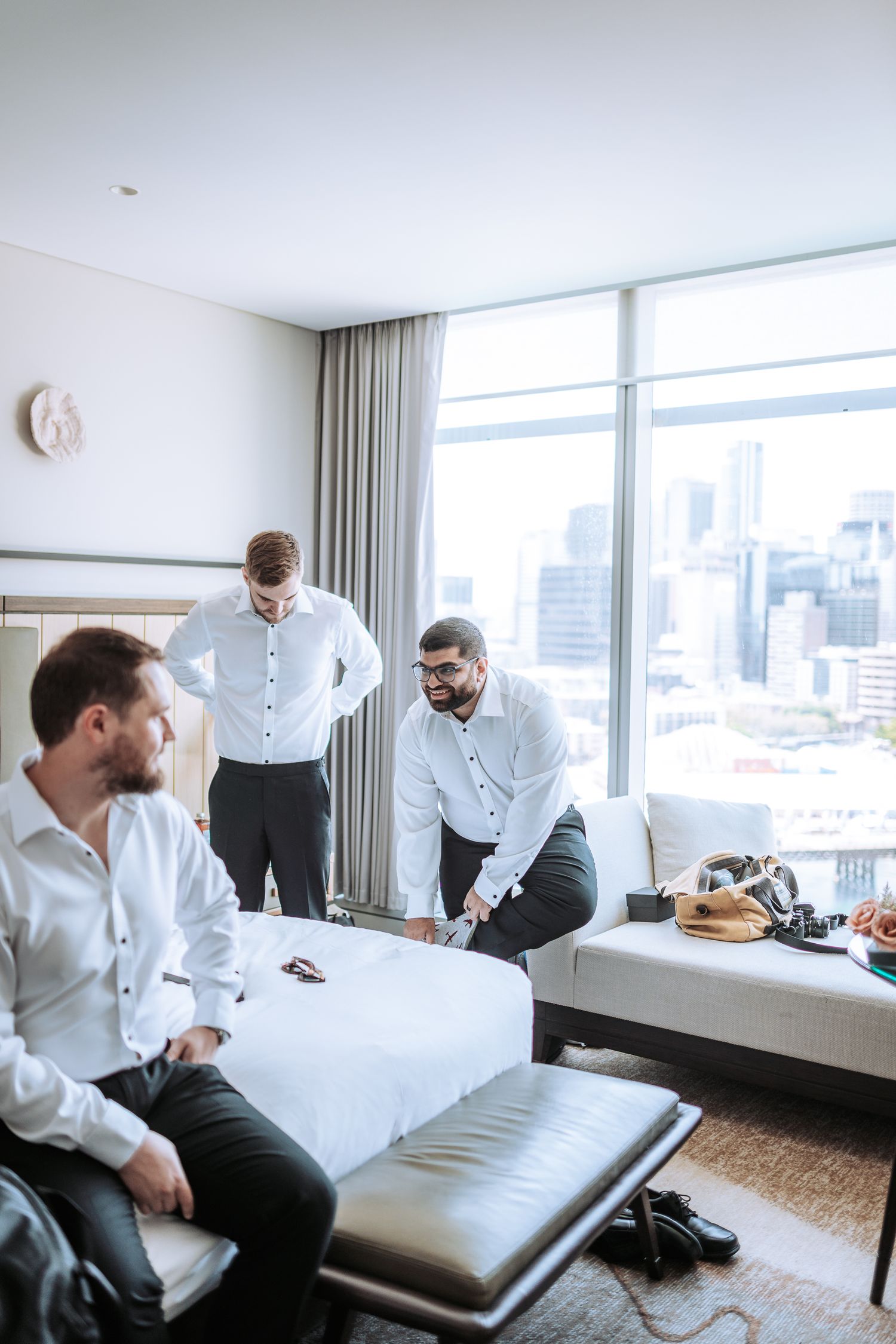 People in white shirts gathered in a modern hotel room discussing something.