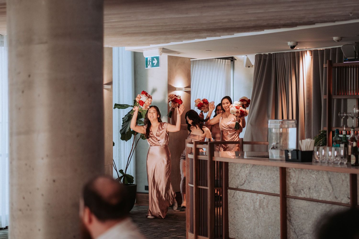 Group celebrates at elegant wedding reception with decorative lighting and bar setup.