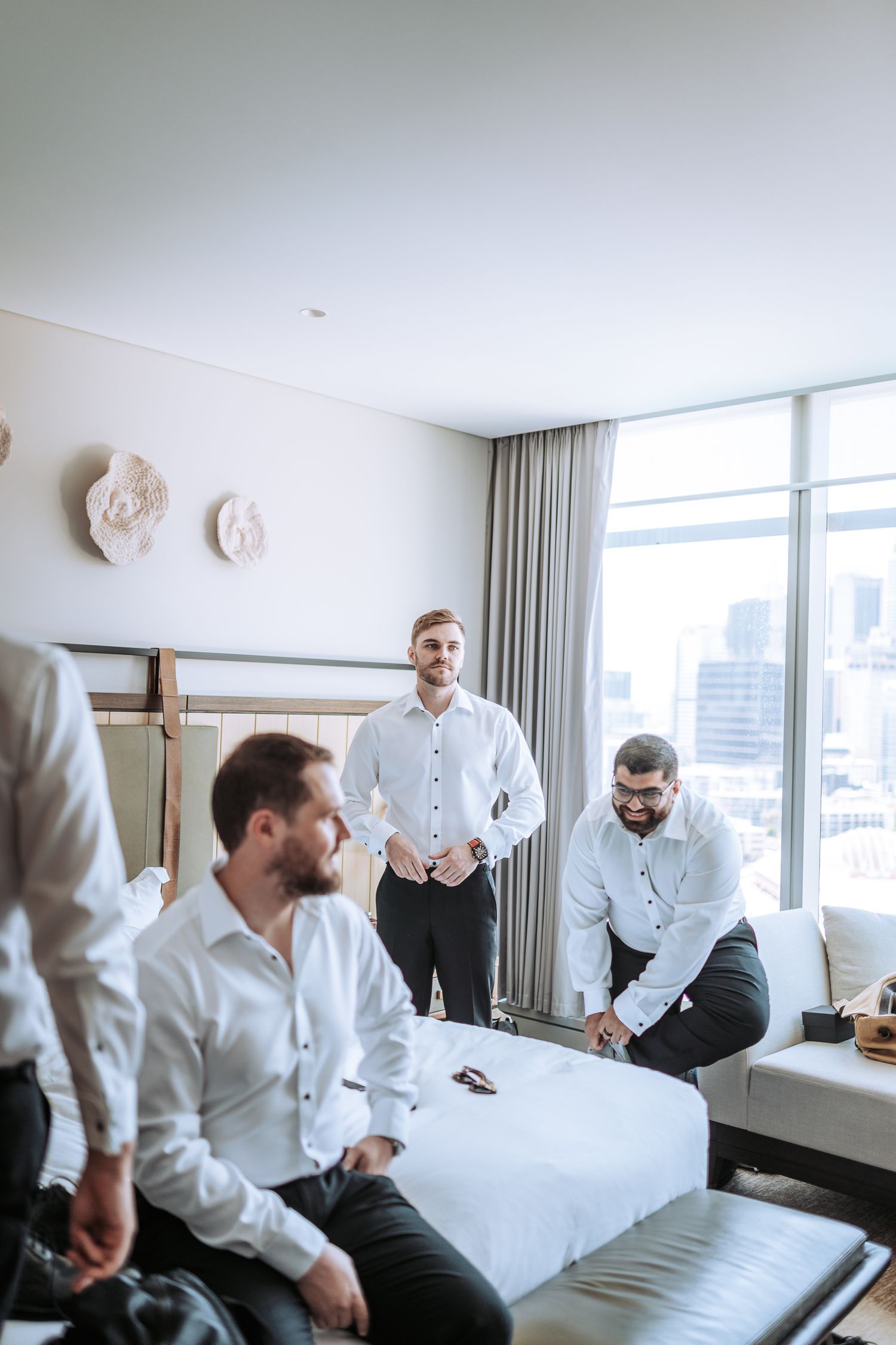 Group meeting in bright hotel room with city skyline visible through windows.