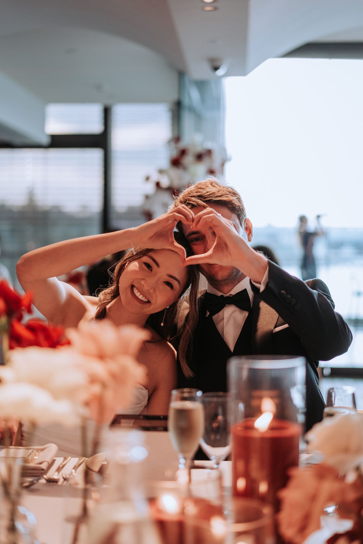 Wedding couple shares joyful moment during reception dinner with decorative table settings.