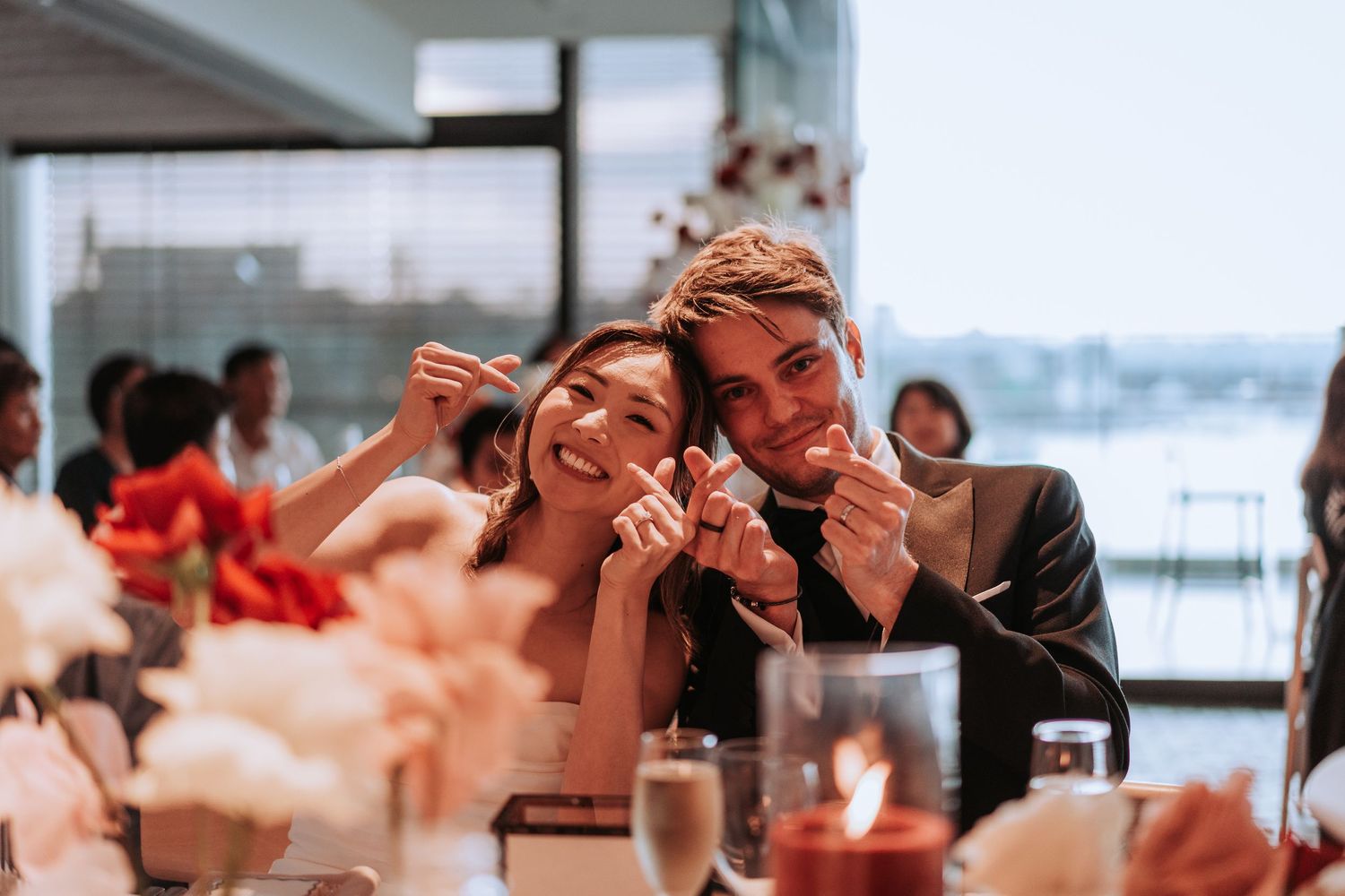 Candid reception moment with couple making funny faces during dinner.