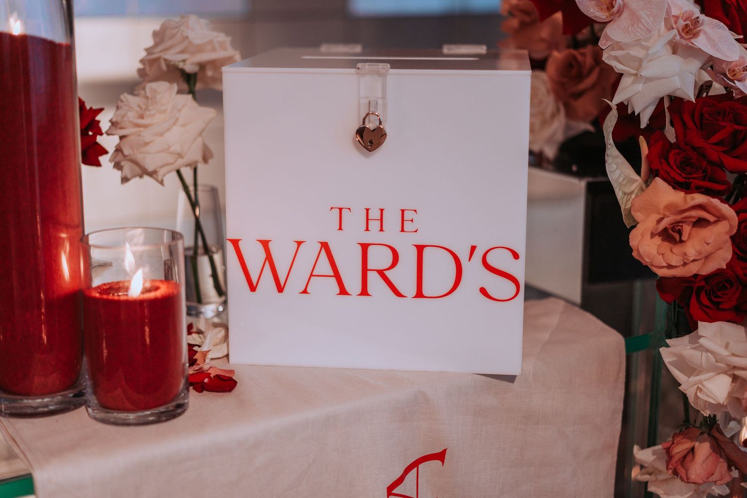Wedding reception detail showing 'The Ward's' sign with red drinks and floral centerpieces.