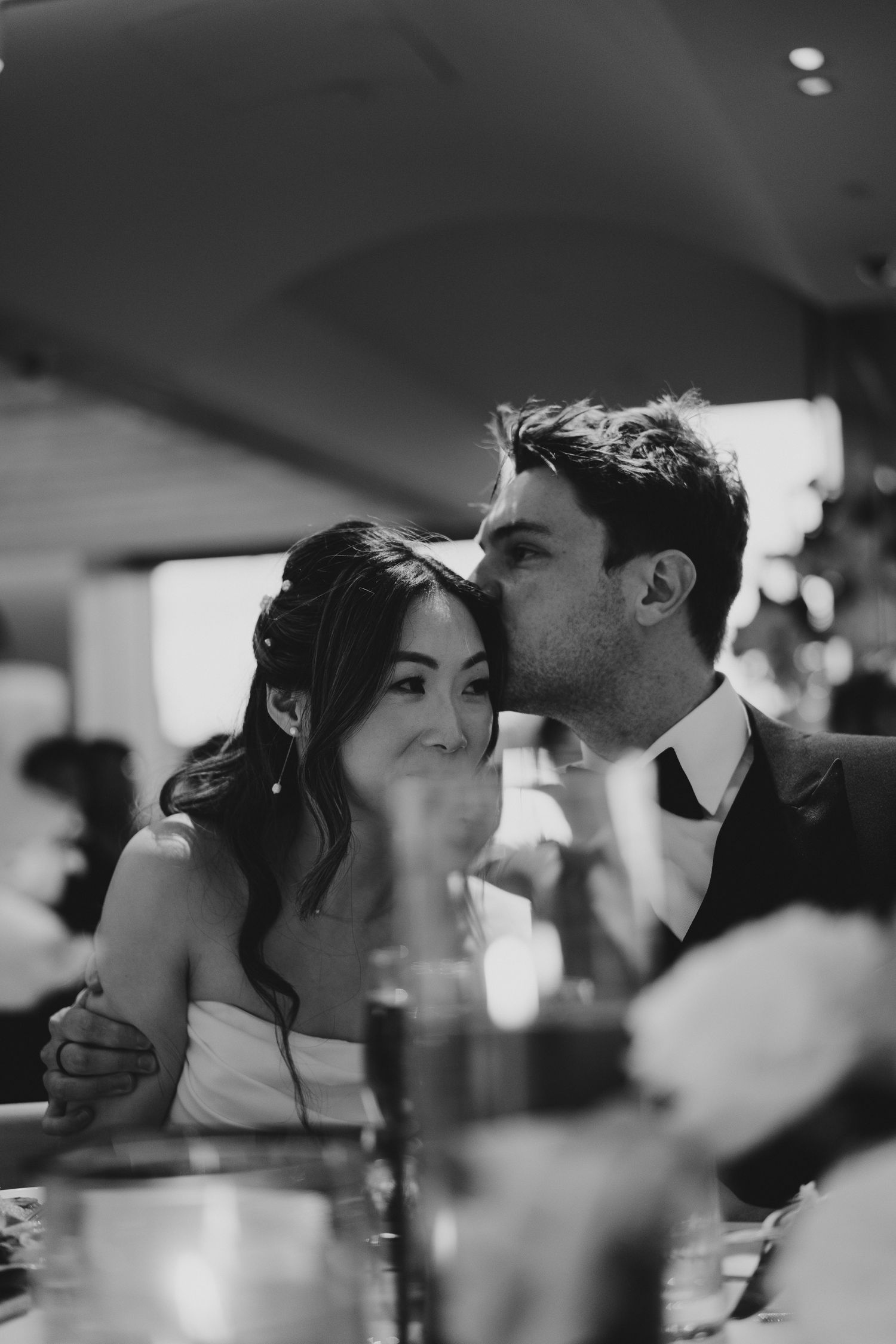 Intimate black and white portrait of couple sharing tender moment at wedding reception.