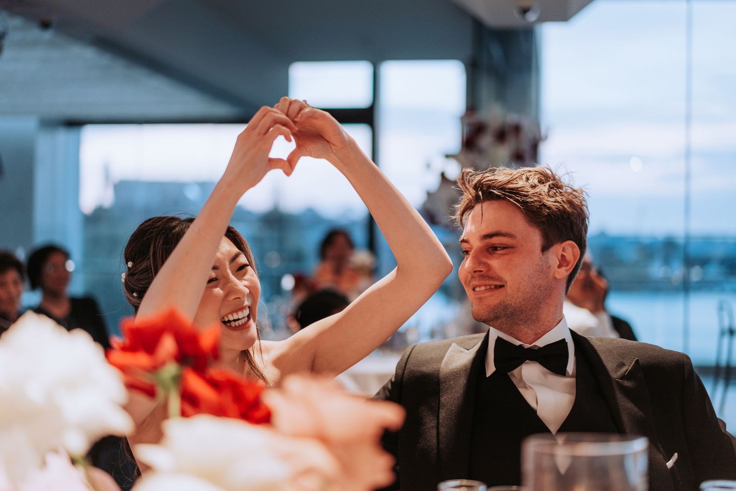 Joyful celebration moment between couple at waterfront wedding reception venue.