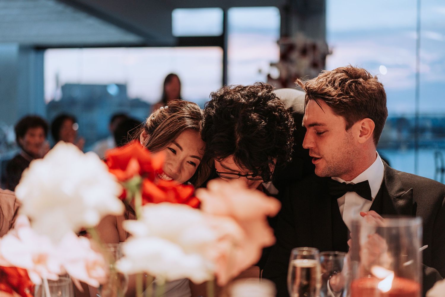 Guests share joyful moments at an elegant wedding reception with floral centerpieces and ocean views.