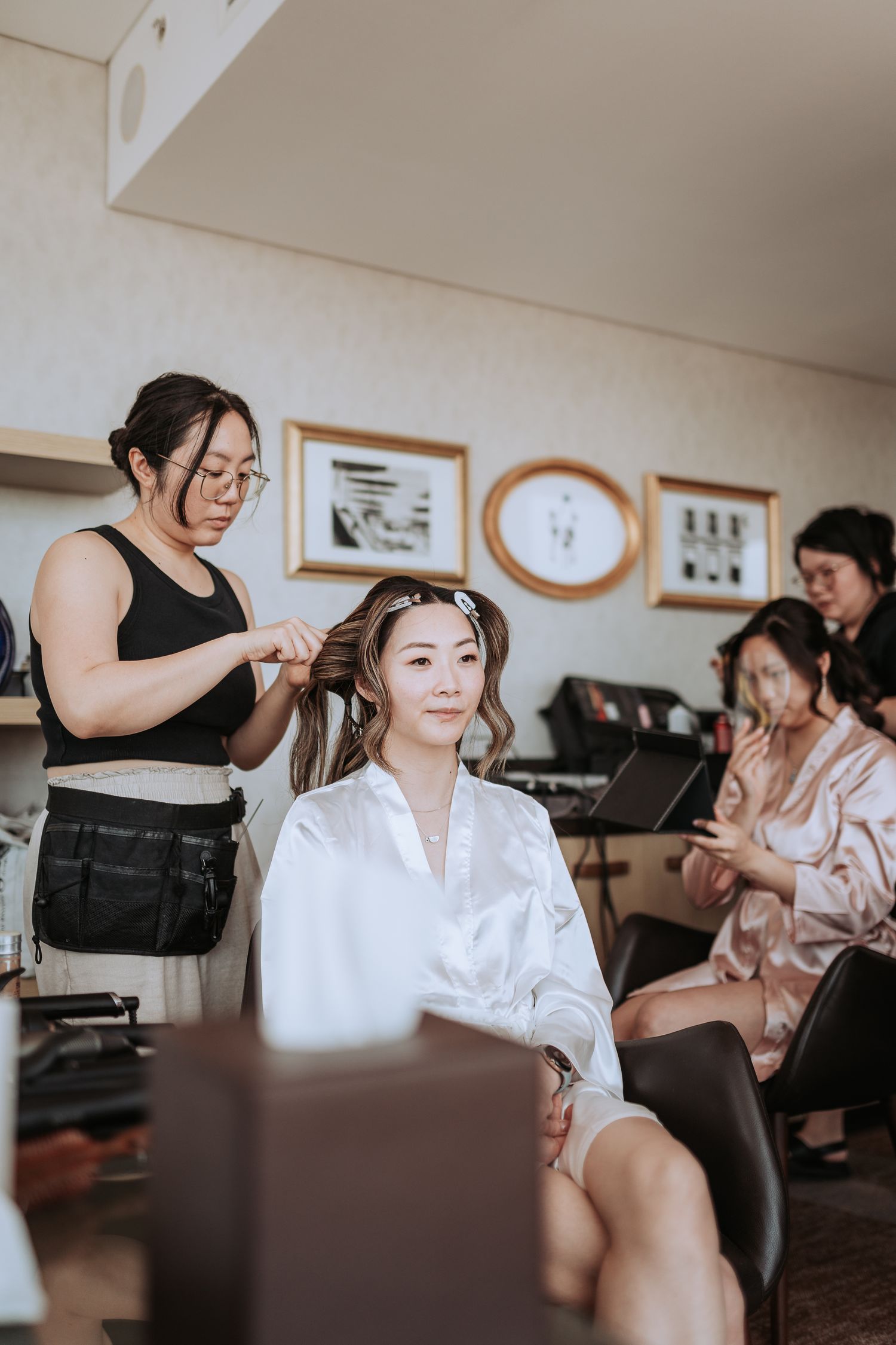 Hair stylist works on bridal preparation in a well-lit getting ready room.