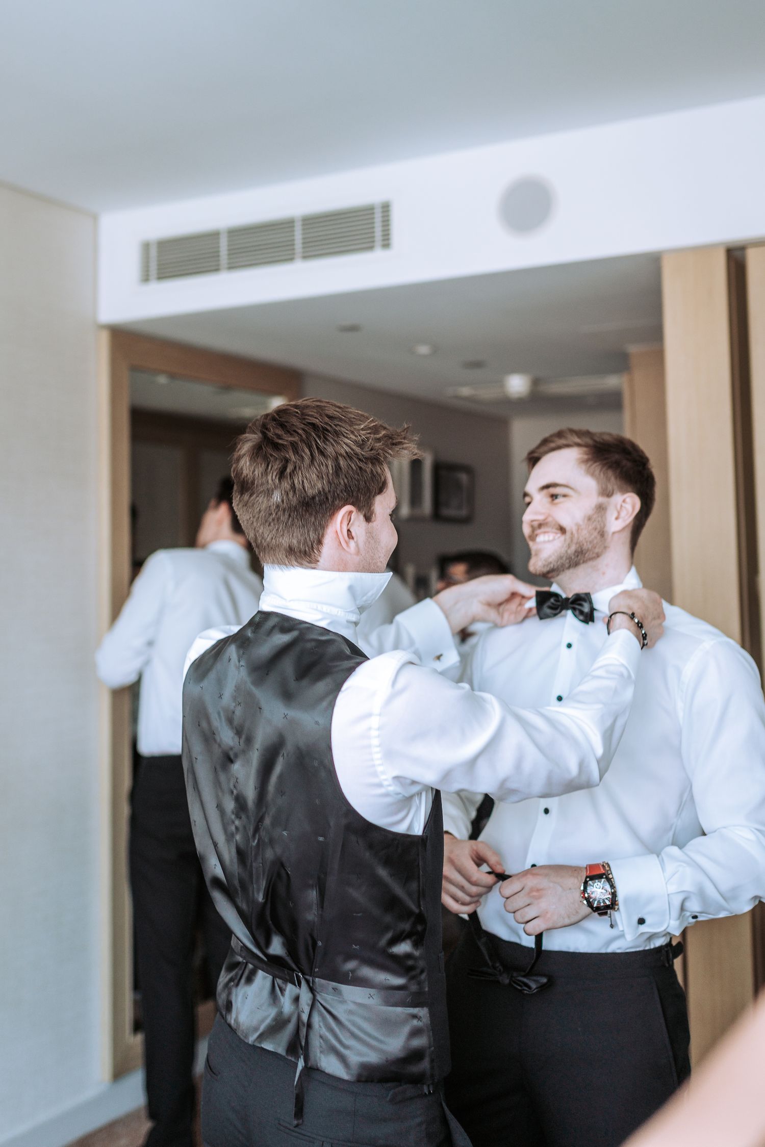 Two people adjusting bow ties while getting ready for formal event.