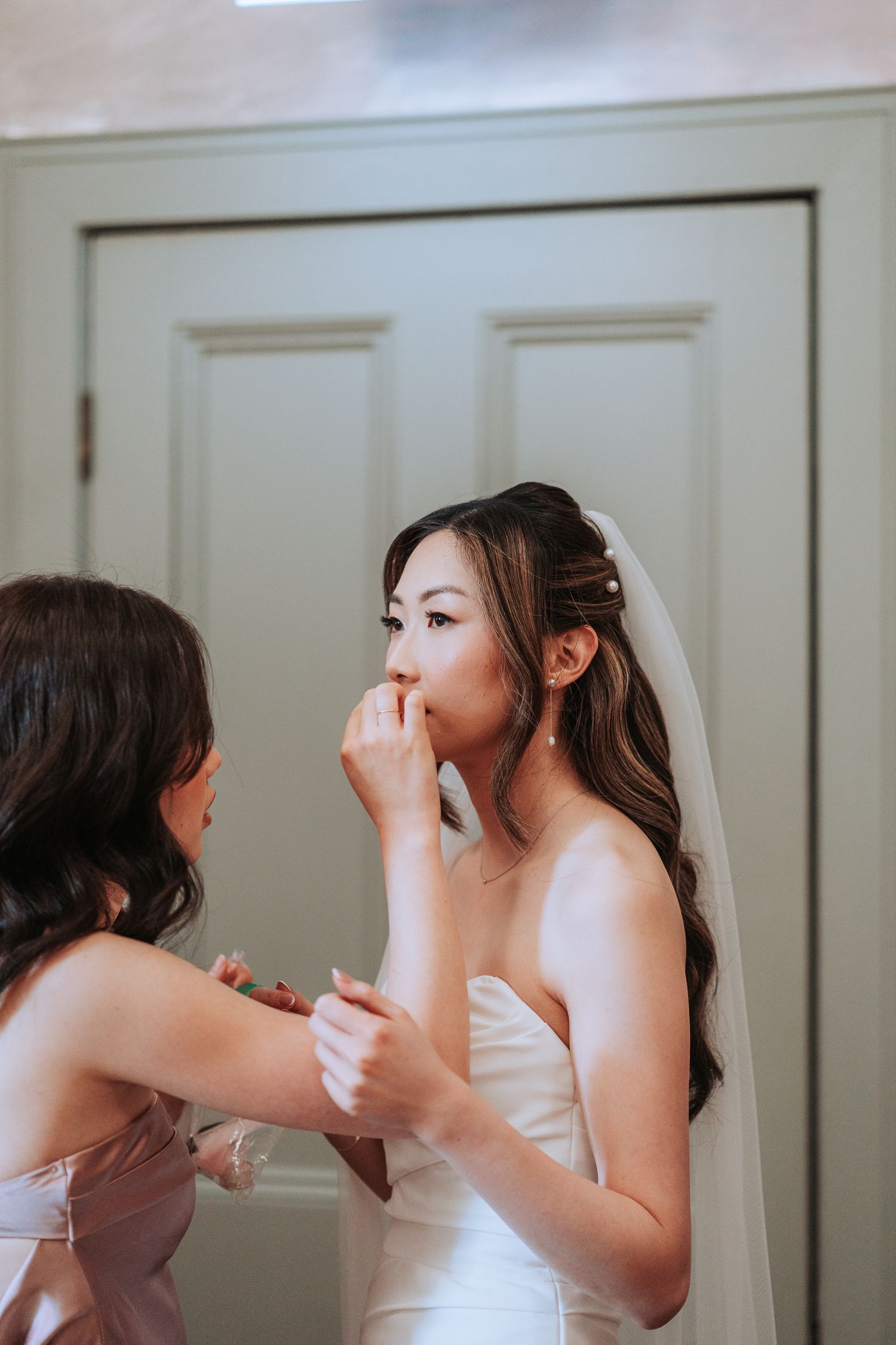 Bride getting final makeup touches done before wedding ceremony.
