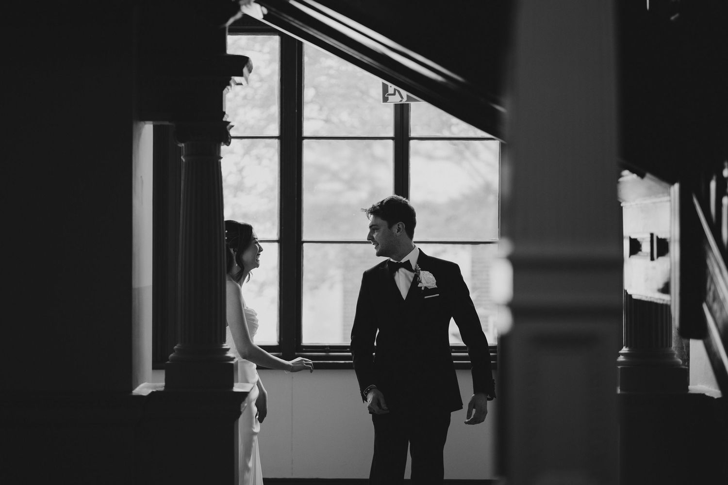 A couple shares an intimate moment in front of a window creating dramatic shadows and light.