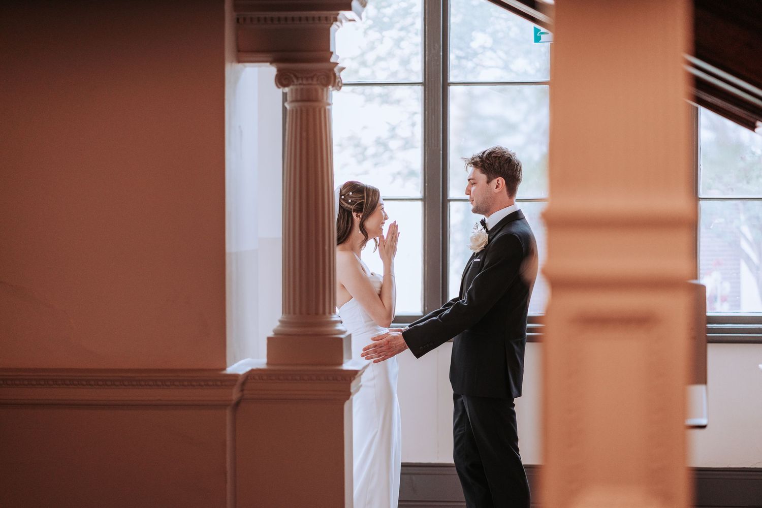A couple shares an emotional first look moment in a room with classic architectural details.