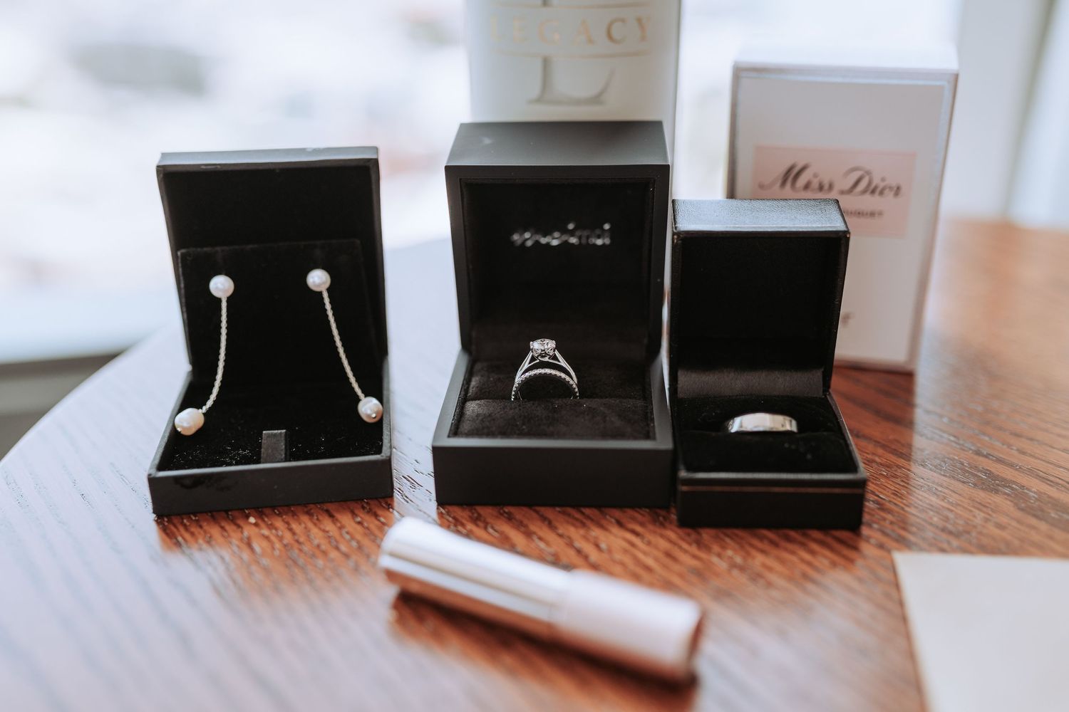 Open jewelry boxes displaying rings and earrings arranged on a wooden surface.