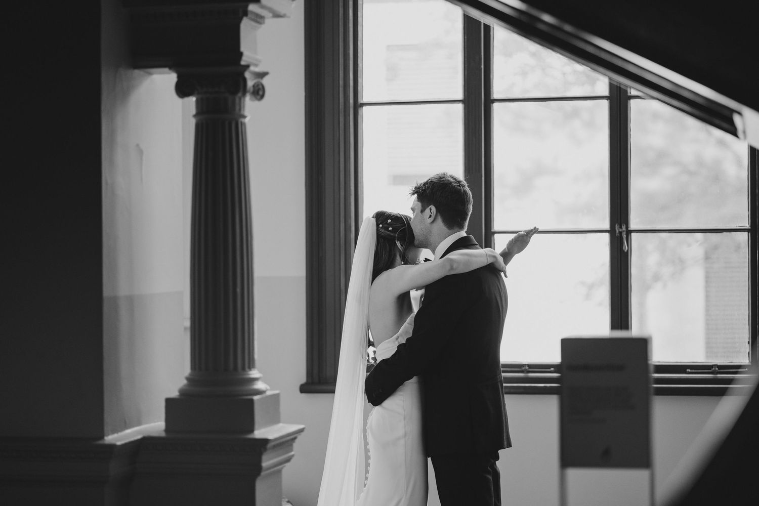A black and white capture of a couple's embrace framed by architectural elements.