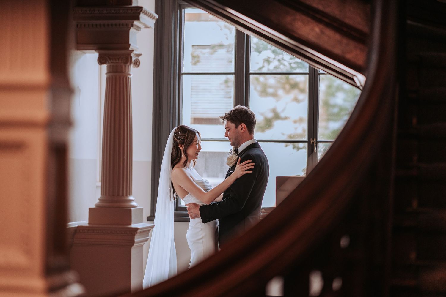 A romantic moment between a couple viewed through architectural elements and warm lighting.