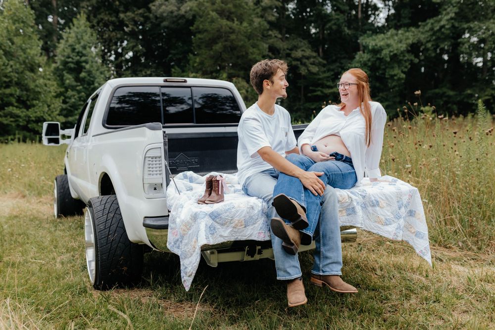 Couple shares candid moments while sitting in back of white pickup truck.