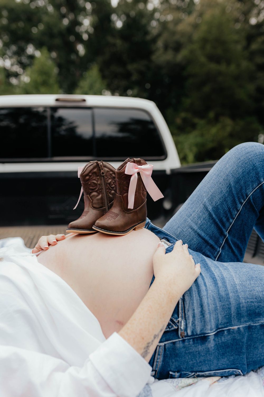 Detail shot of brown boots and casual attire during rustic outdoor maternity session.