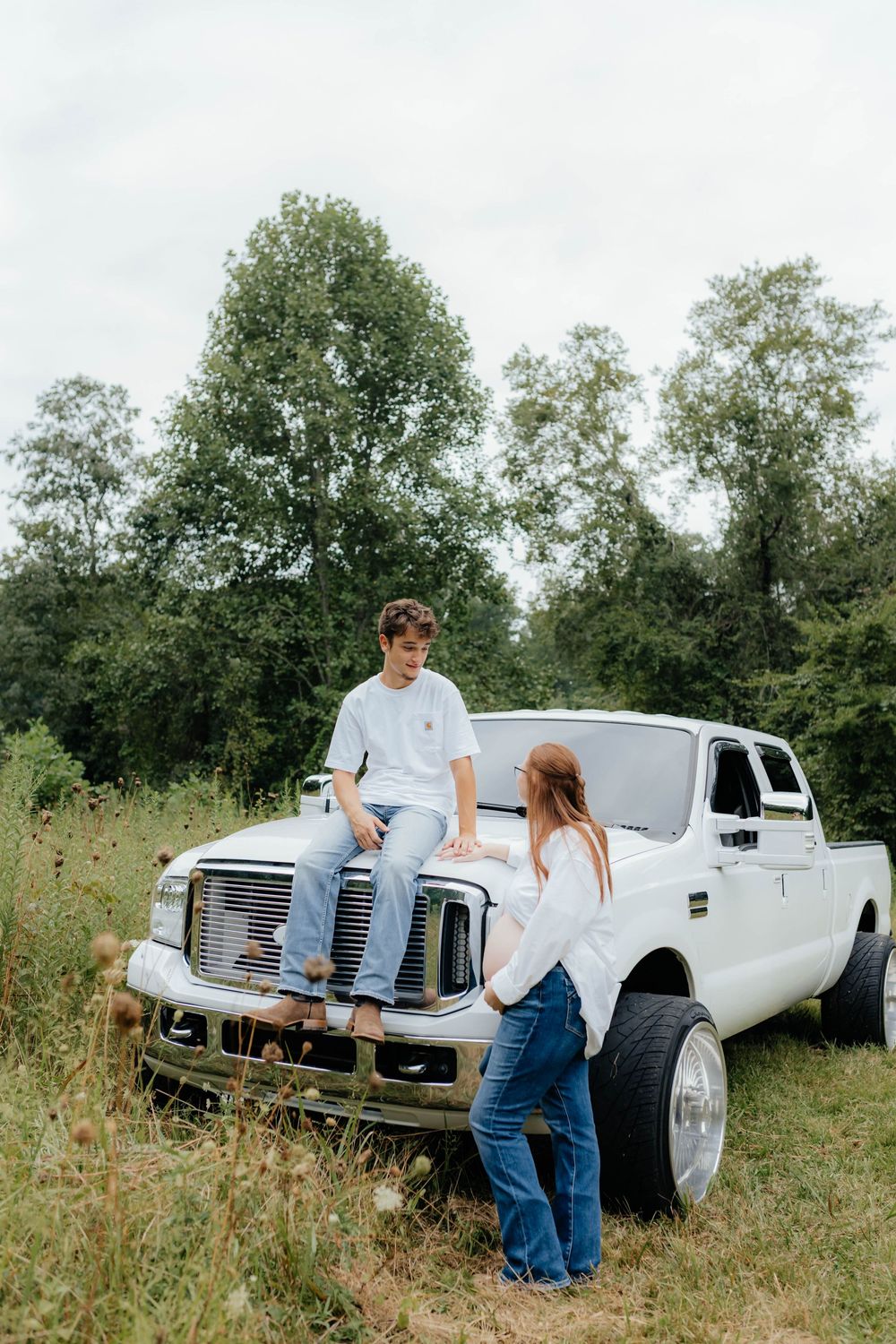 Classic white truck serves as backdrop for outdoor photography session in a rustic field.