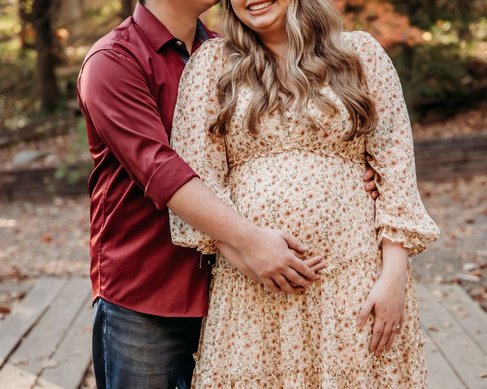 Couple embraces in polka dot dress and burgundy shirt during autumn photoshoot.