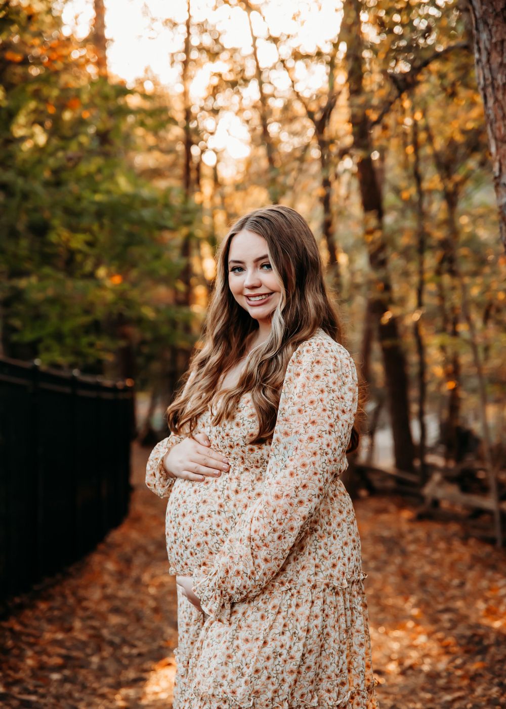 Woman in polka dot dress smiles during autumn forest photoshoot.