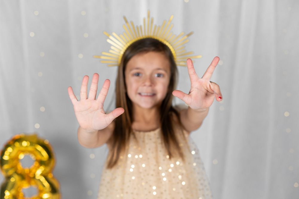 Celebratory photo with gold crown effect and peace sign gesture against white backdrop.