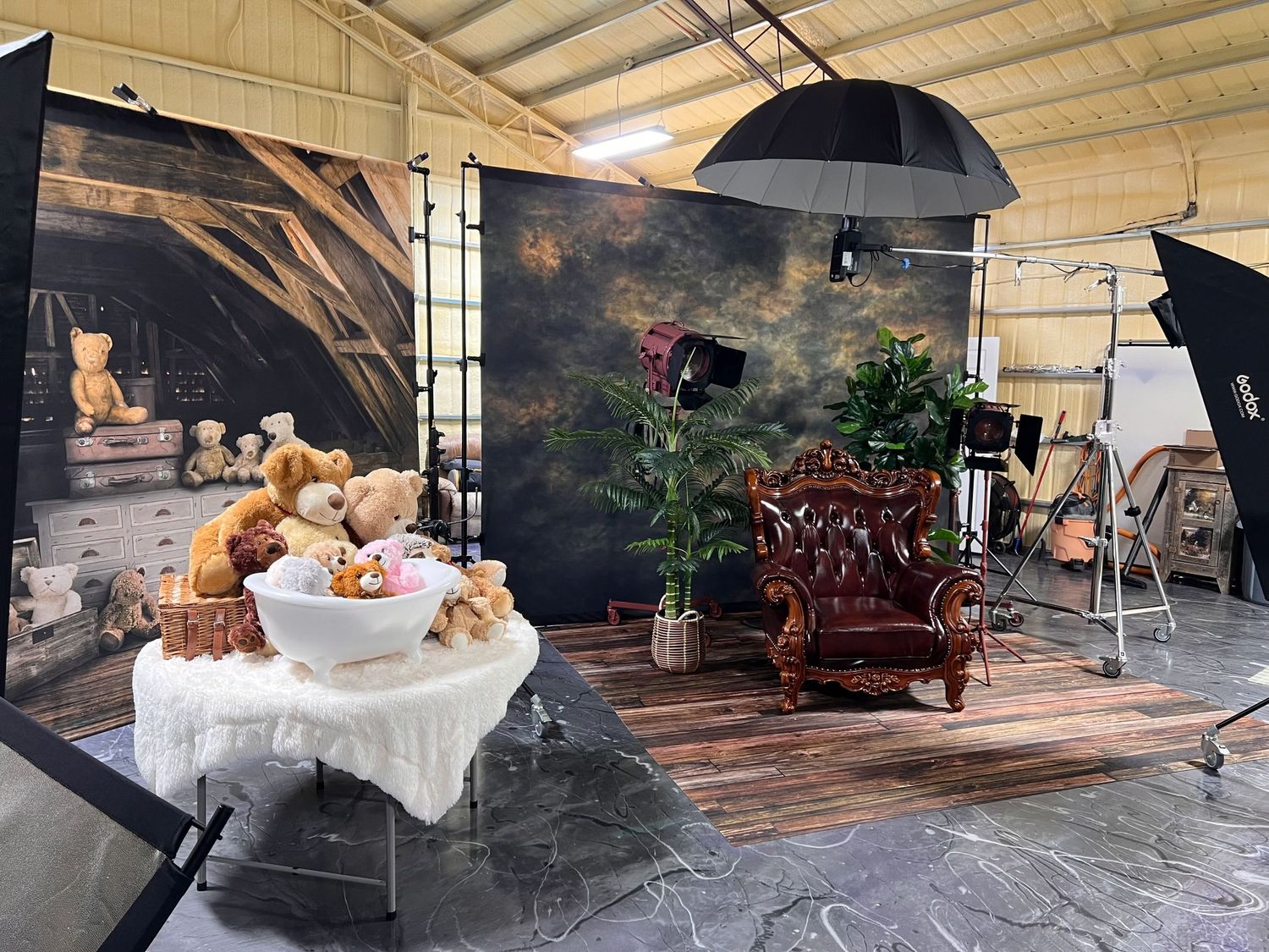 Photography studio setup with antique chair, dramatic backdrop, and various props and lighting equipment.
