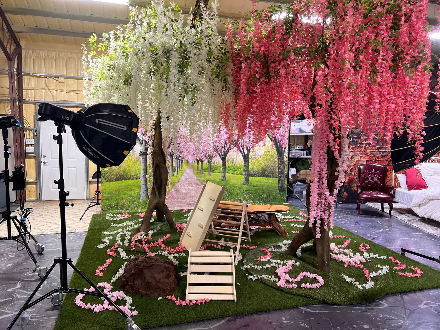 Enchanting garden scene with pink and white wisteria flowers hanging over wooden bridge and artificial grass.