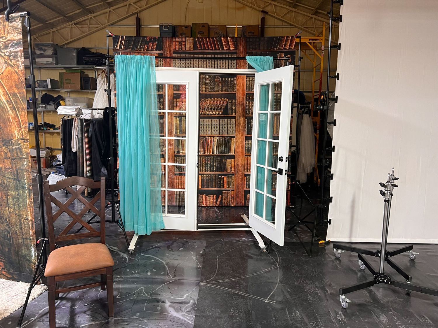 Photography studio set with French doors, turquoise curtains, and bookshelves as backdrop.