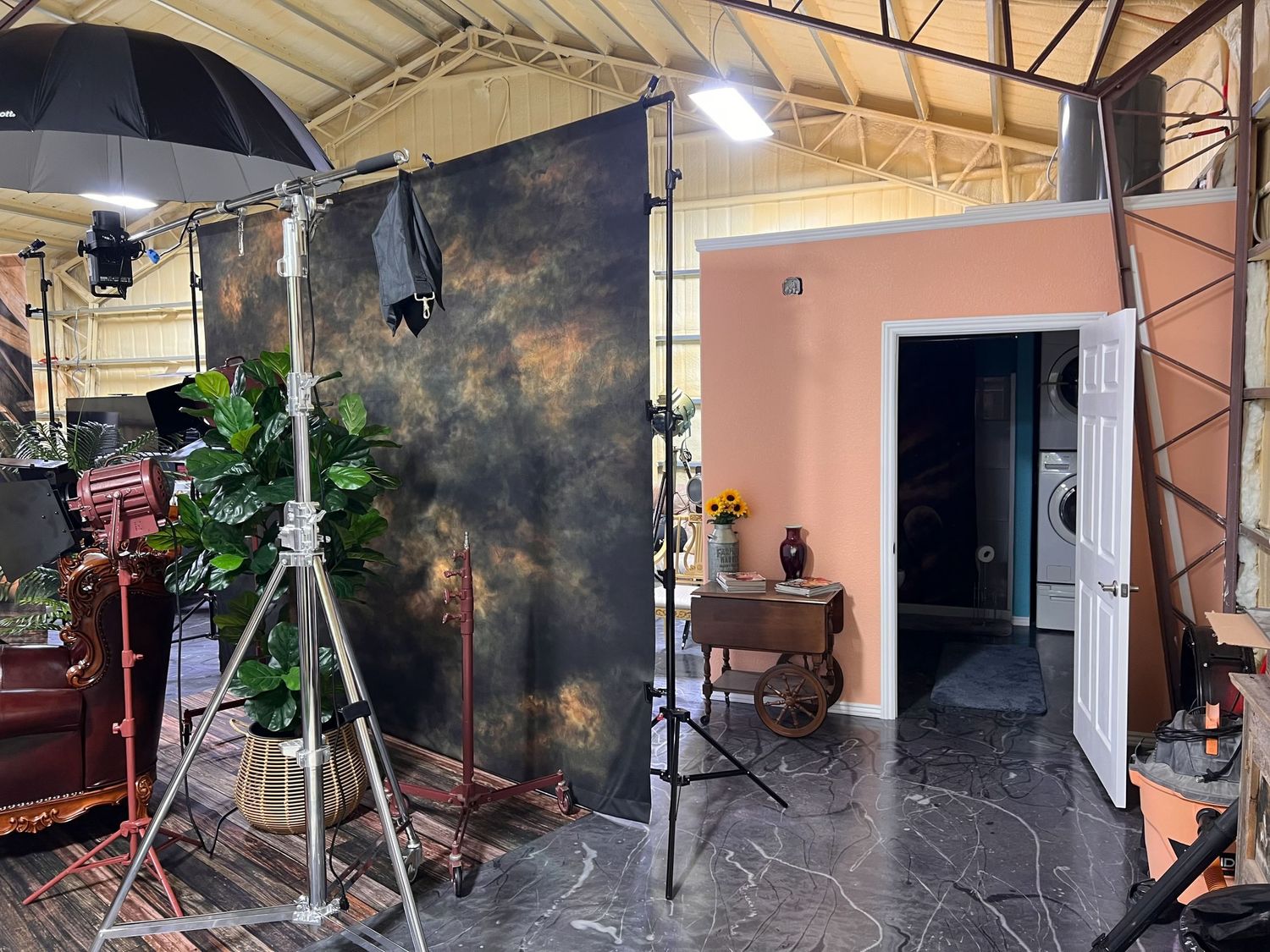 Interior of photo studio showing lighting equipment, backdrops and vintage furniture setup.