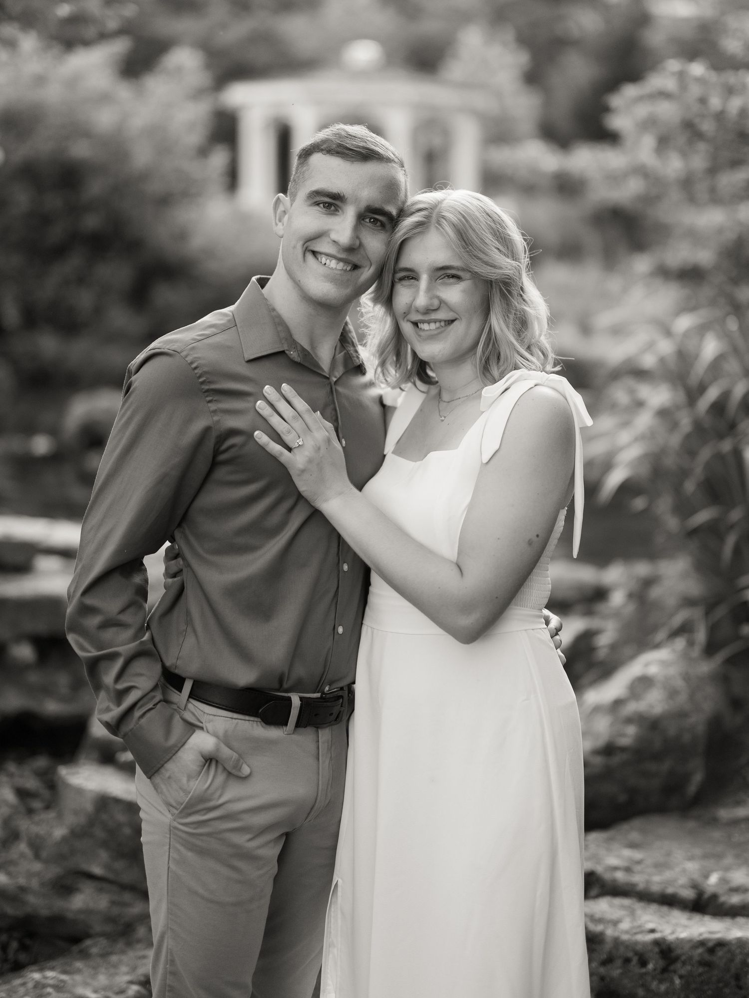 Black and white romantic photo series showing couple sharing playful and intimate moments in an outdoor garden setting.