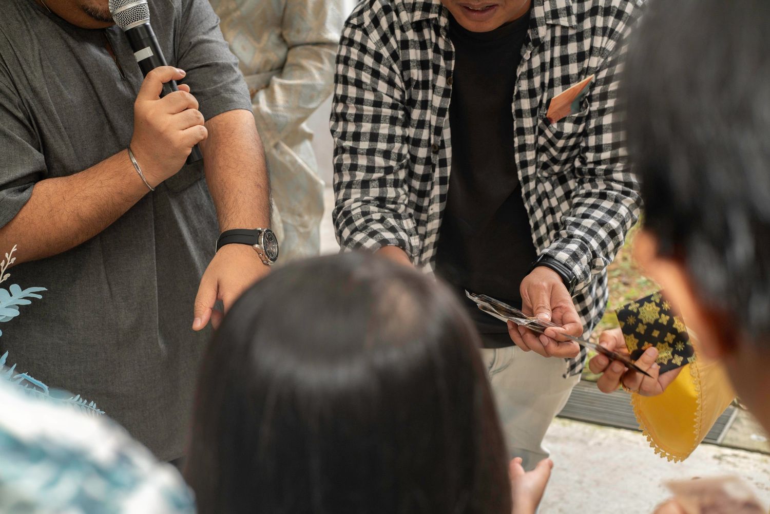 People sit around a table playing board games and writing on paper while having a casual group gathering.