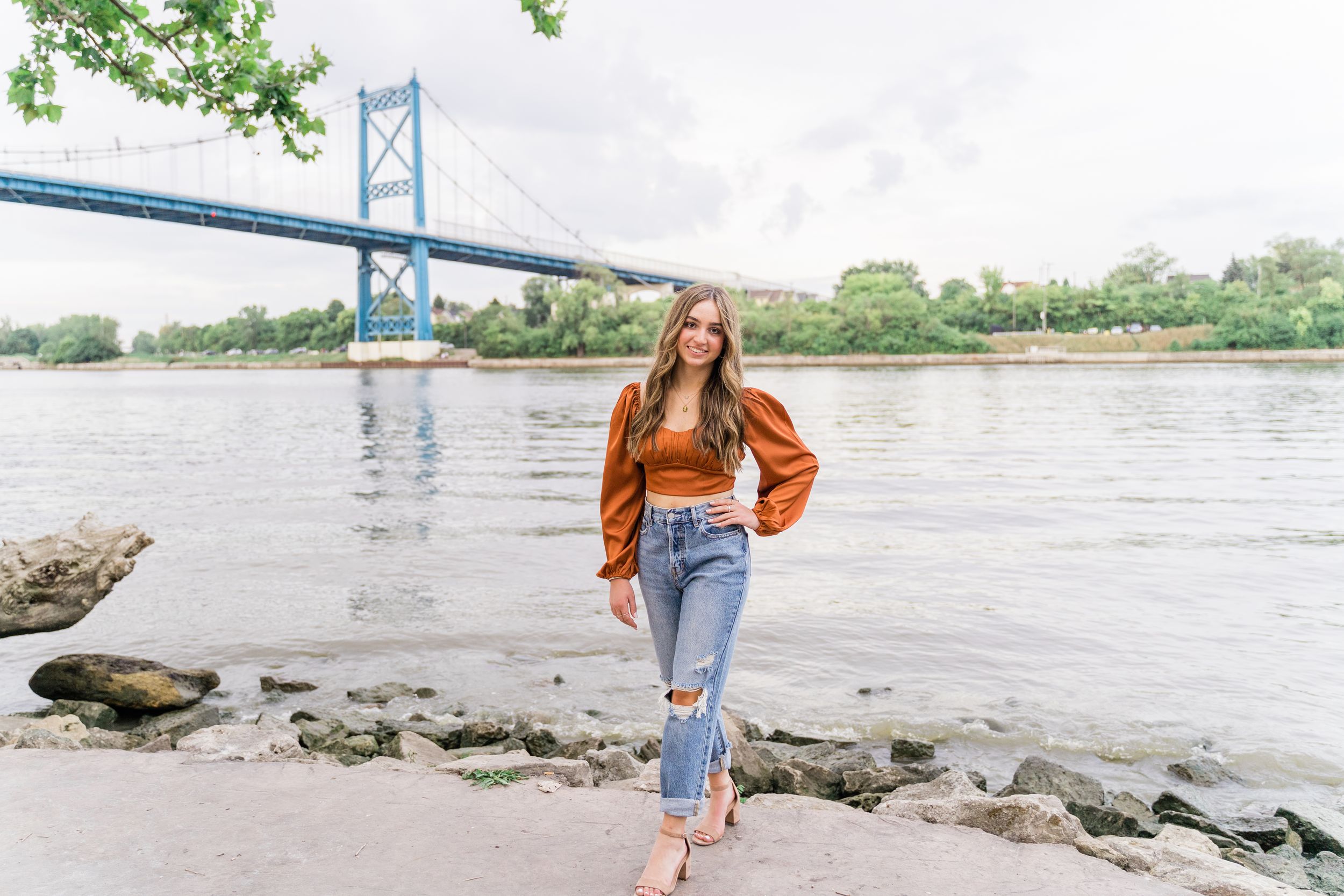 Lifestyle photos taken near a bridge with rocky shoreline and water views on a cloudy day.