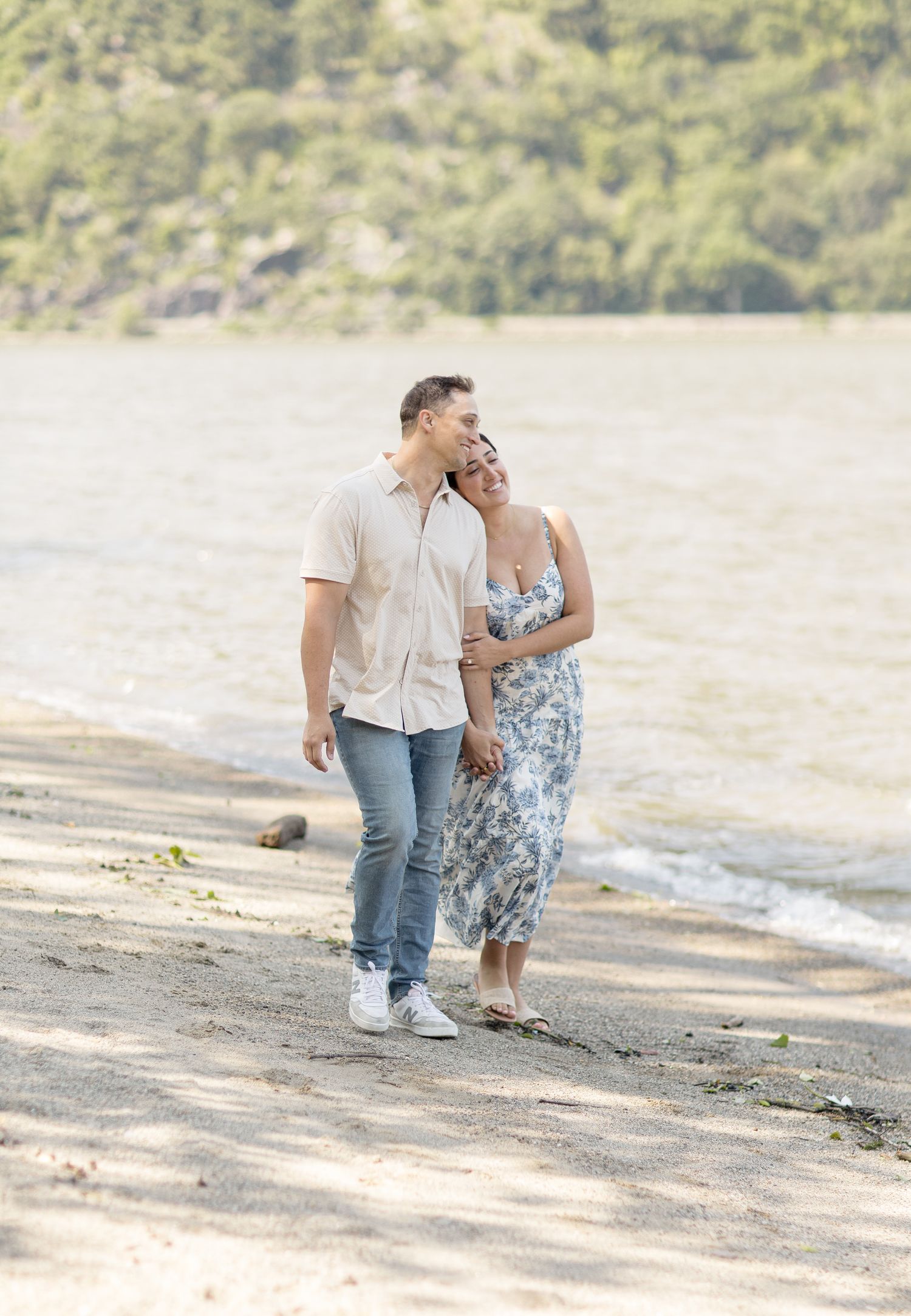 A couple takes a romantic stroll along the shoreline on a sunny afternoon.