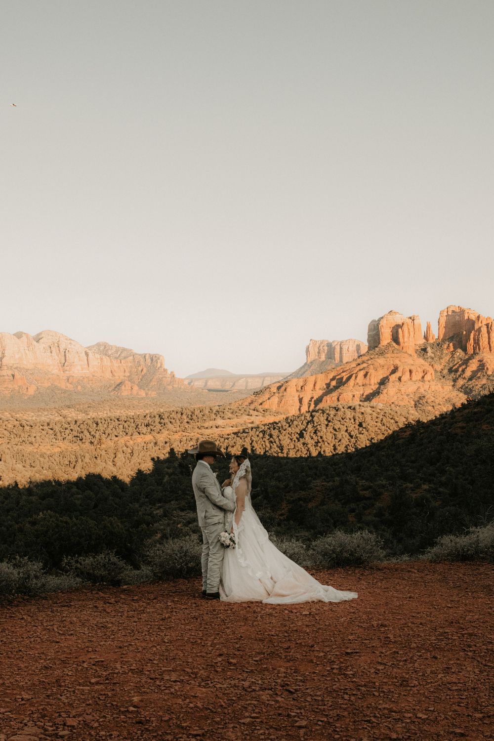Bride and groom embracing under desert mountains during their Arizona wedding.