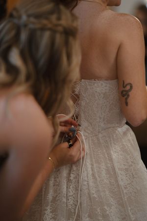 Detail shot of lace wedding dress being fastened.