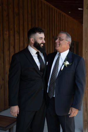 Wedding party members in black suits share a candid moment.