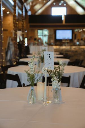 Wedding reception tables decorated with simple white floral centerpieces and table numbers.