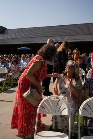 Wedding guests in colorful dresses participate in a group toast outdoors.