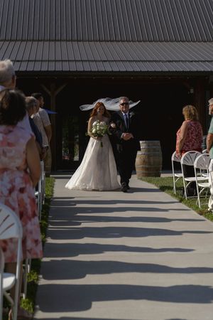 A wedding ceremony setup with white chairs and guests arriving at an outdoor venue.