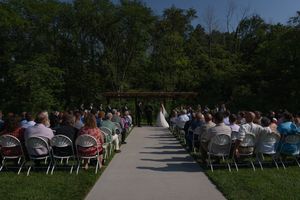 Panoramic view of wedding guests seated in rows of white chairs during an outdoor ceremony.